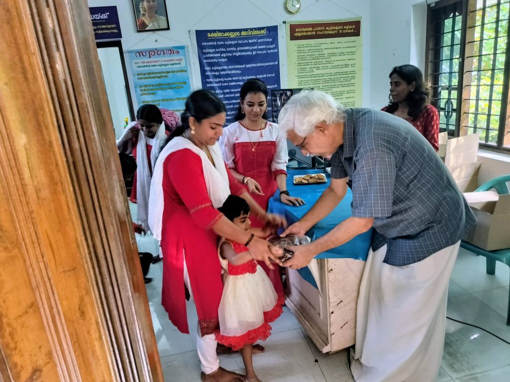 A society member sharing sweets with a child at the guidance centre